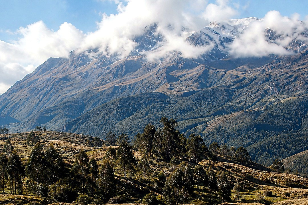 Snow-covered alpine valley with mountain peaks and wooden cabins.